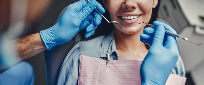 Woman smiling at the camera while dentist performs dental work